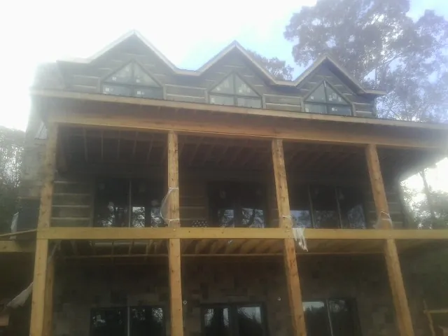 Dormers and porch framing on a large log home under construction — Roof Coating work by our crew in Carbondale